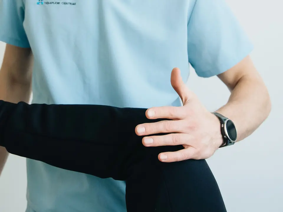 Clinician examining a patient's knee during a specialist musculoskeletal assessment